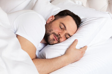 View of handsome smiling man  sleeping in his bed at home.