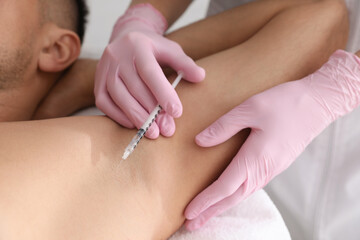 Obraz na płótnie Canvas Cosmetologist injecting man's armpit, closeup. Treatment of hyperhidrosis