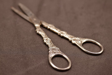selective focus on filigree of the base of an old silver scissors on brown velvet background