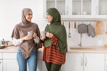 Happy Senior Muslim Mother And Daughter Drinking Coffee In Kitchen