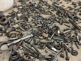 Lots of nuts and bolts on the floor in the auto repair shop. Scattered parts.