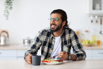 Happy middle-eastern young man enjoying healthy lunch at home