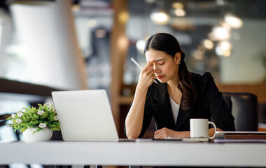 Asian women sitting in a home office With stress and eye strain.Tired businesswoman holding...