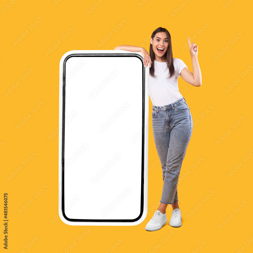 Poster woman showing white empty smartphone screen and pointing up