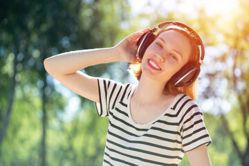 Young woman happens to have music in a summer park