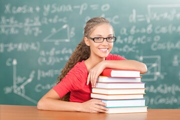 Happy positive school teacher against classroom interior background with books