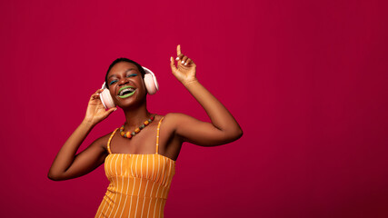 Joyful african american woman listening to music, using wireless headphones