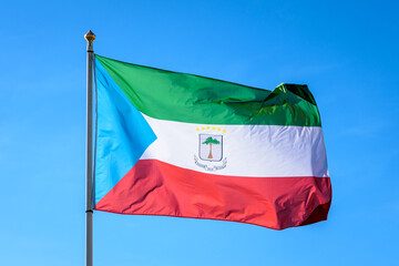 Naklejka na ściany i meble The national flag of Equatorial Guinea is flying in the wind at full mast against blue sky.