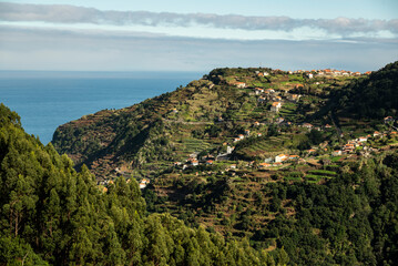 Panoramic view of the houses of Ribeira da Janela village and the surrounding terraced landscape, seen from the “Levada da Ribeira da Janela” hiking trail, Madeira, Portugal