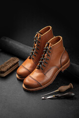 Handcrafted brown leather shoes with cobbler tools on the backgound