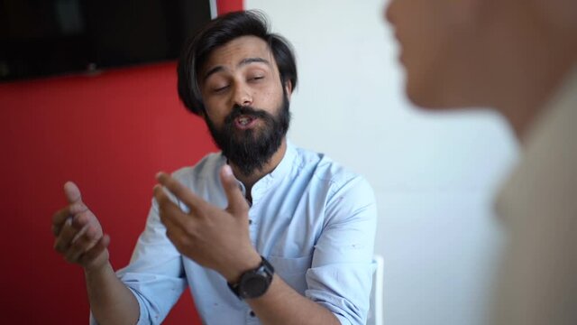 Close-up of confident Indian male insurer consulting young man client about insurance benefits in office. Closeup of unrecognizable vacancy candidature applicant answers question during job interview.