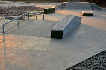 Skateboard park with concrete cement surface with concrete skateboard obstacles is designed for roller sports. Cycling is not allowed except for freestyle bikes. icing winter morning sunrise