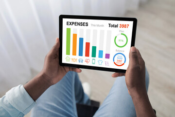 Man in wheelchair using digital tablet at home, planning budget