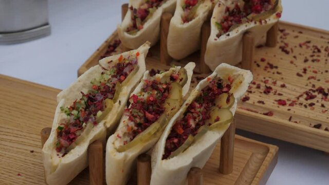 Pita on a wooden stand. Rows of vegetarian pita with pickled cucumber and vegetable wedges
