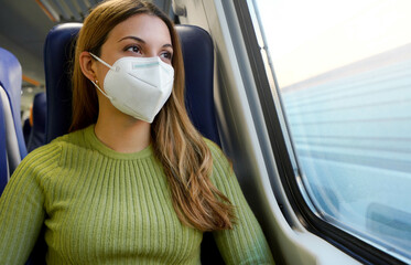 Portrait of young woman wearing protective face mask FFP2 KN95 on public transport looking through...