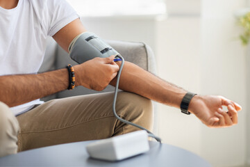 Unrecognizable male patient using modern tonometer at home