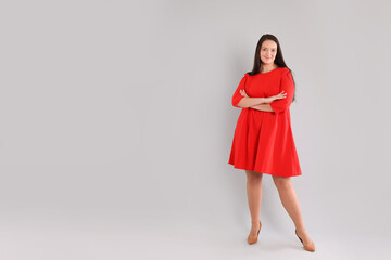 Beautiful overweight woman in red dress on light grey background. Space for text