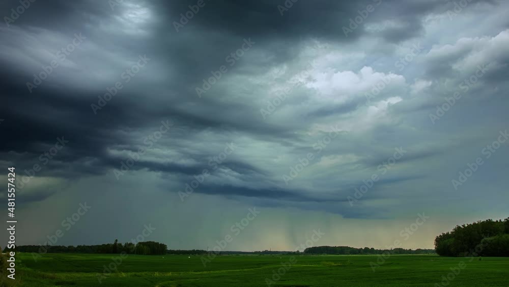 Aufkleber timelapse video of black stormy rain clouds blowing over the green field with the view of forest tre