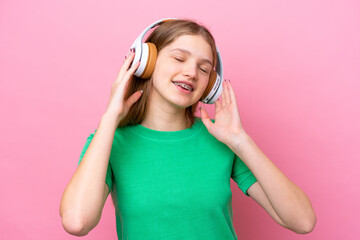 Teenager Russian girl isolated on pink background listening music and singing