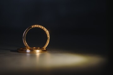 Elegant wedding rings for the bride and groom on a black background with highlights, macro, selective focus