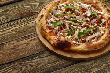 croped shot of neapolitan Pizza with Mozzarella cheese, bacon, ham, tomato sauce, chicken, Spices and Fresh arugula. Italian pizza on wooden table background