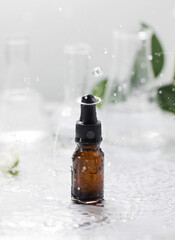 Glass dropper bottle with essential oil on wet table under falling down drops