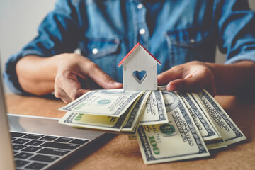 house wooden and banknote us dollar bills in hand ,Tax ,Property investment and mortgage financial concept.