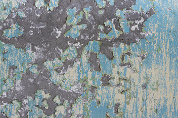 Peeling paint on the wall. Old concrete wall with cracked flaking paint. Weathered rough painted surface with patterns of cracks and peeling. Grunge texture for background and design. High resolution.