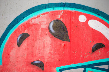 Fragments of a watermelon painted on the wall. The wall is painted with spray paint. Concrete graffiti wall texture.