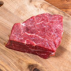 Raw piece of fresh beef on a wooden cutting board close-up