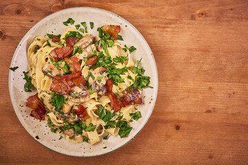 Fettuccine with champignon creamy mushroom sauce and fried pancetta, bacon on a plate, top view, copy space - traditional italian pasta