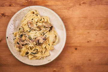 Fettuccine with creamy champignon mushroom sauce on a plate, top view, copy space - traditional italian pasta