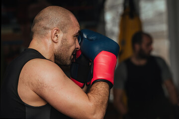 A male athlete of a strong physique, a boxer stands in a boxing stance and is ready to strike. He...
