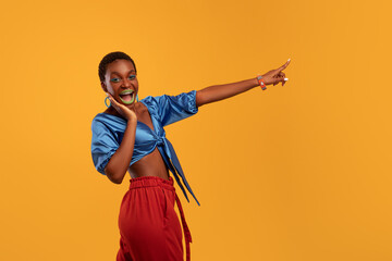 Emotional stylish african american young woman pointing at copy space