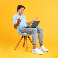 Excited guy using laptop celebrating success sitting on chair