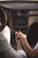 Close up shot of loving couple traveling by car and holding hands. Summer background. Focus on hands of man and woman in a road trip.