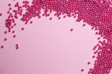 Bright beads on pink background, flat lay. Space for text