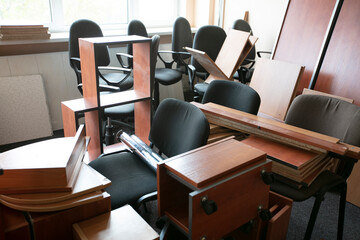 Lots of disassembled and scattered office furniture in an empty room.