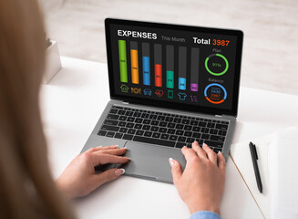 Woman using laptop at office, checking her expenses