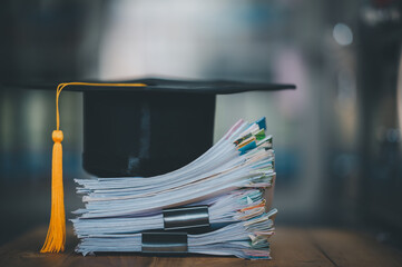 Graduation cap lays on a pile of papers at the desk,concept education for work