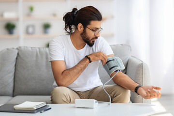 Middle-eastern man checking blood pressure at home