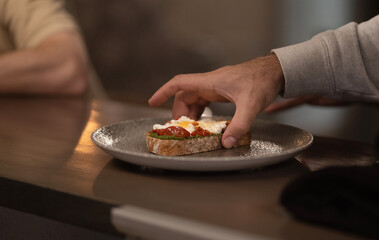 A man's hand takes a sandwich from a plate in a cafe. Food concept