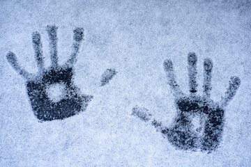 Imprints of two hands on white snow. Call for help.