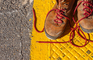 Workboots on a yellow man hole cover, on a construction site pavement.