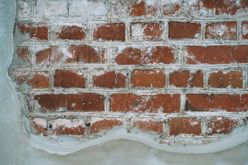 Photo of the texture of an old brick and a deformed layer of plaster.