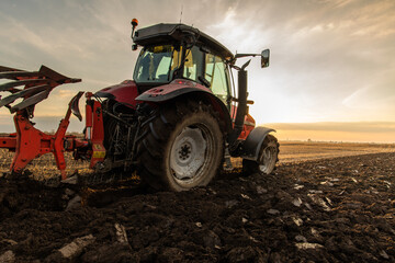 Obraz premium Tractor on the field during sunset.