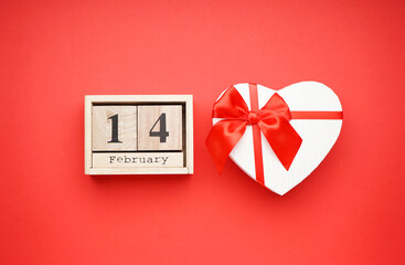 Gift box with a wooden calendar for Valentine's Day on a red background, flat lay.