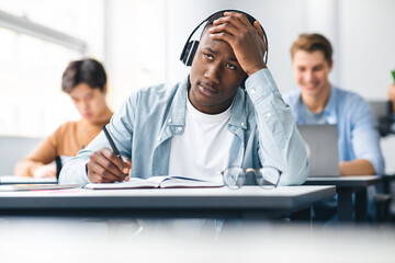Black male student writing sitting at desk in class