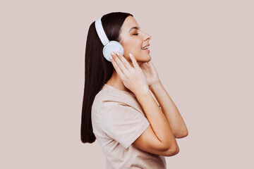 Beautiful young brunette woman girl in beige shirt posing isolated on beige wall background studio...