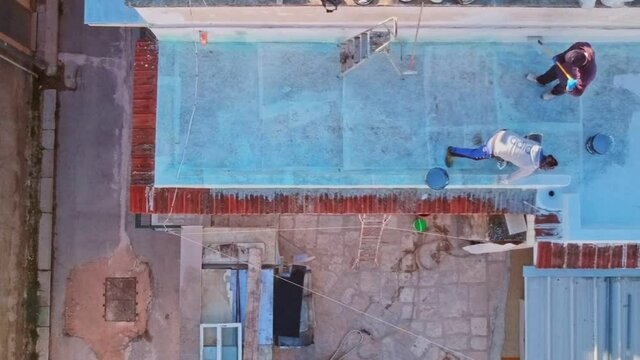 Aerial view with the drone of workers who carry out the waterproofing of a terrace with resin, making the surface pedestrian and with excellent aesthetics
